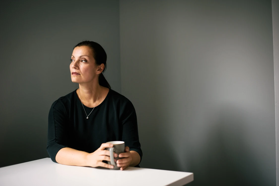 Frau sitzt mit tasse in einem raum