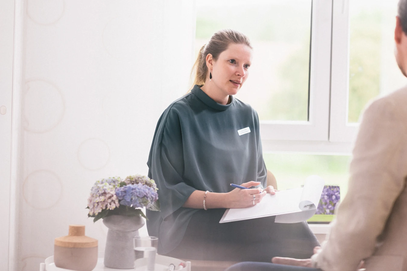 Therapeutin macht sich im Gespr&auml;ch Notizen auf einem Klemmbrett